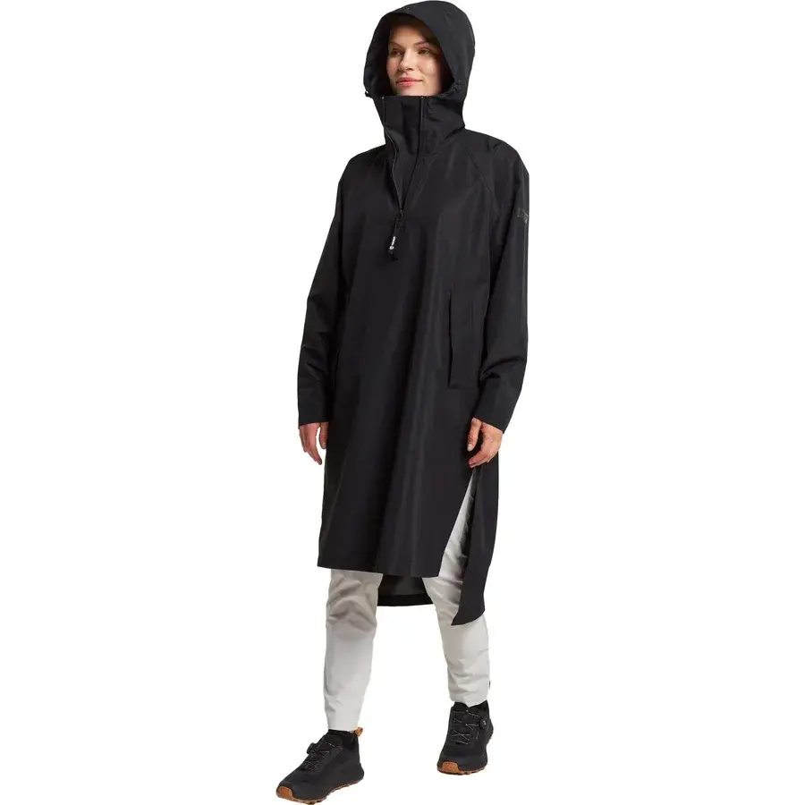 Sort Tenson Drizzle Poncho med hætten oppe, høj krave og kort lynlås, båret af en kvinde og set skråt forfra